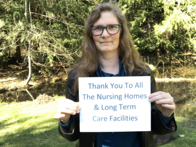 Nancy is holding a thank you sign in appreciation for all Pandemic workers.